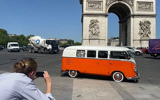 Photo du van Volkswagen orange Clementine garé devant l'Arc de Triomphe